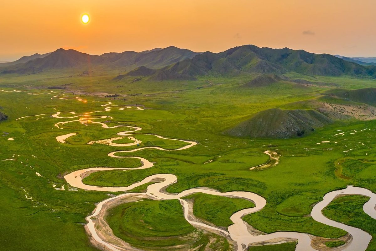 Meandering river across green steppe at sunset, Mongolia
